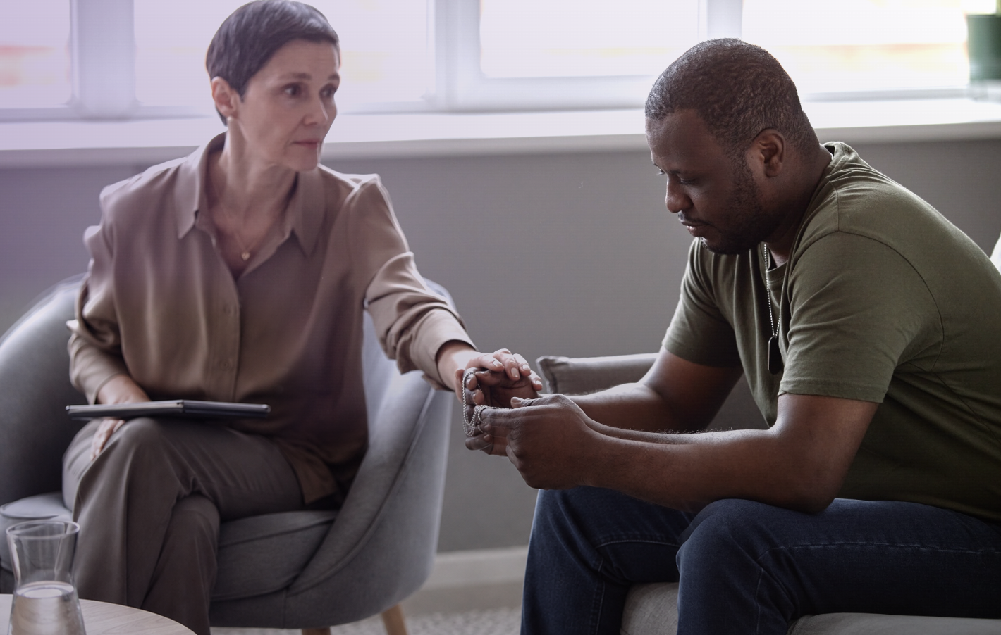 A counselor gently holding the hands of a veteran during a session